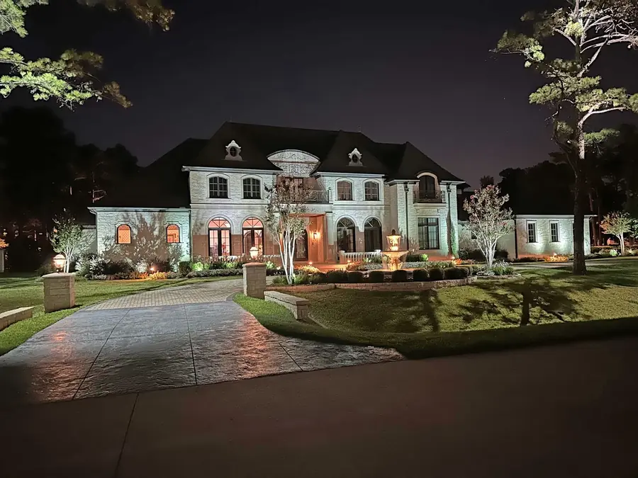 Limestone estate in Dallas, Texas with a lit stone fountain, uplit facade and stamped concrete driveway