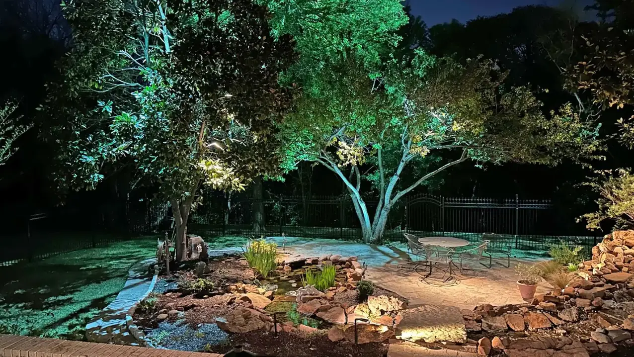 Landscape lighting by TC Lighting on a Colleyville, Texas property after dark — uplit trees and a lit water feature