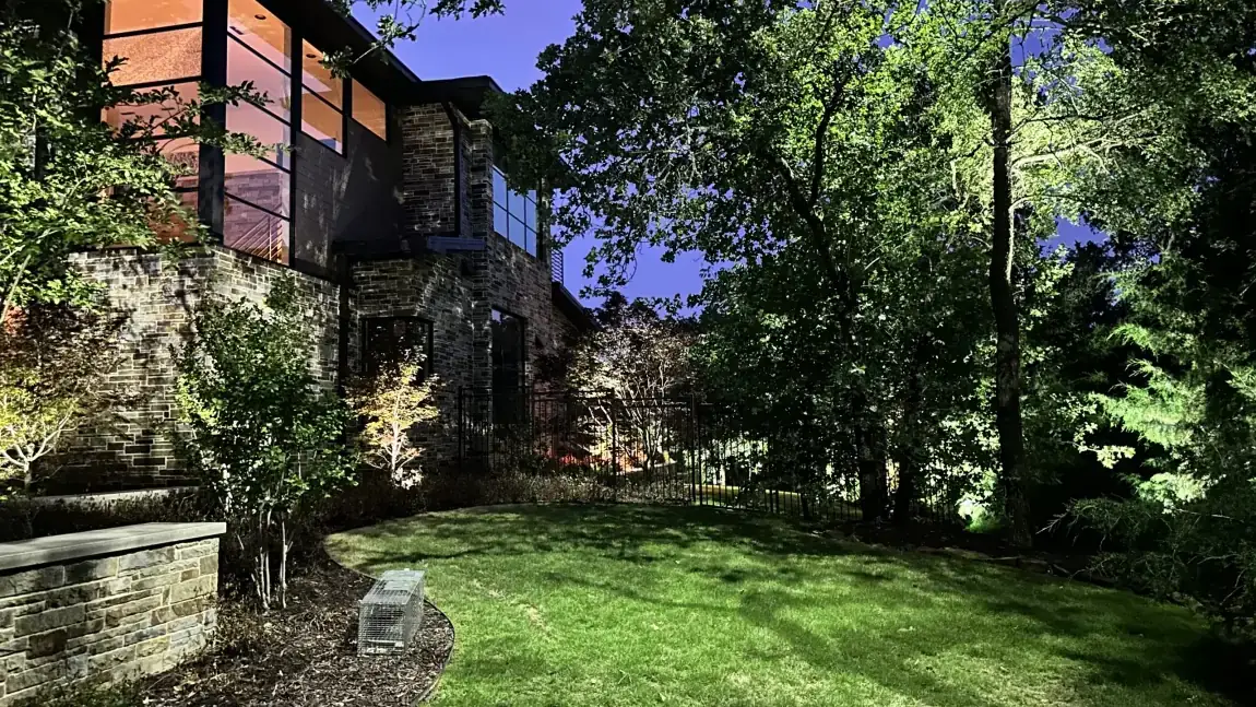 Landscape lighting by TC Lighting on a Flower Mound, Texas property after dark, with uplit trees over a lit garden