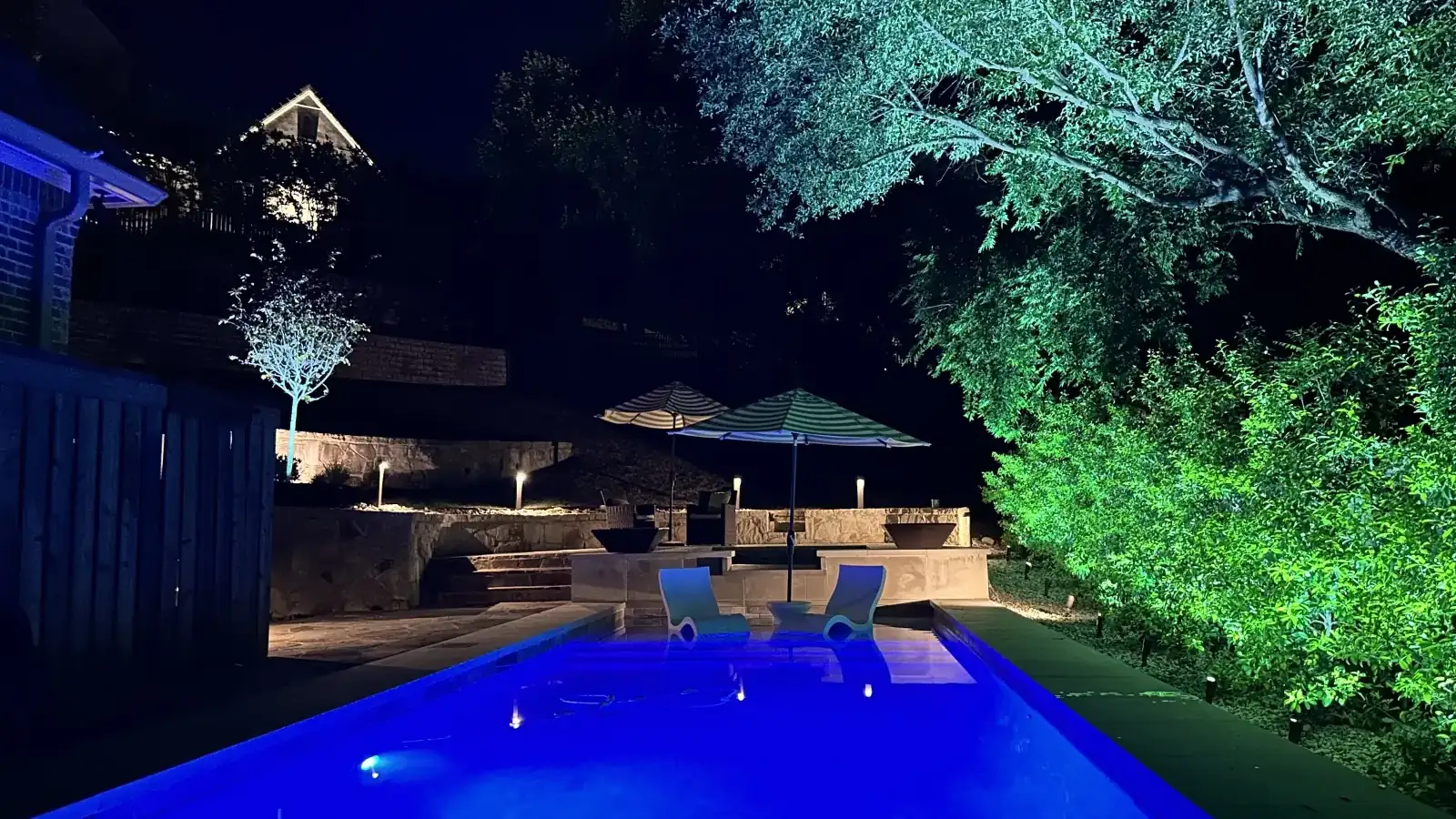 Landscape lighting by TC Lighting on a Fort Worth, Texas property after dark, with uplit trees and lit stonework